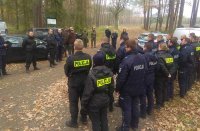 Policjanci i strażnicy leśni stoją na zbiórce i słuchają założeń ćwiczenia