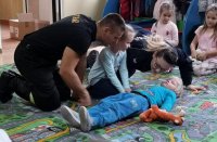Policjantka i strażak uczą dzieci jak sprawdzić czynności życiowe